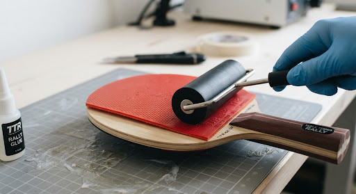 Applying red table tennis rubber to a wooden blade